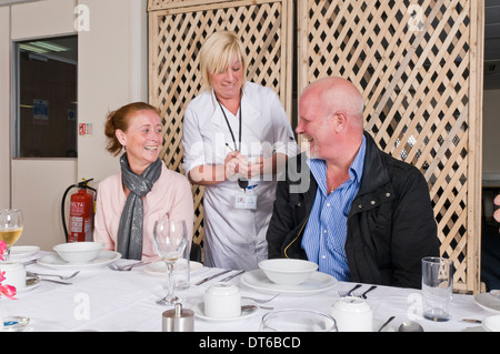 Group of people sat around a dinner table ordering food Stock Photo