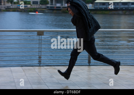 Businessman running to shelter from rain Stock Photo