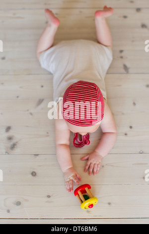 Baby girl lying on floor with toy Stock Photo