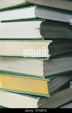A stack of old hard cover books, with worn edges and paper that is stained or yellowed with age and use. Stock Photo