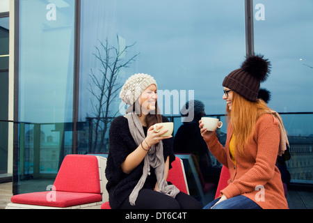 Two young adult women enjoying coffee on rooftop terrace