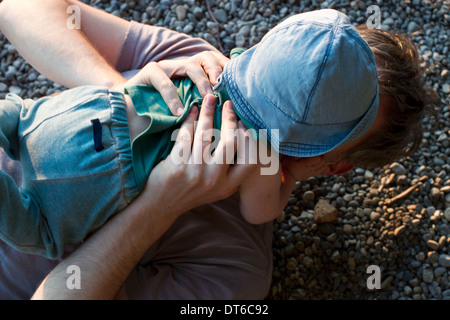 Father lying on ground holding baby daughter Stock Photo