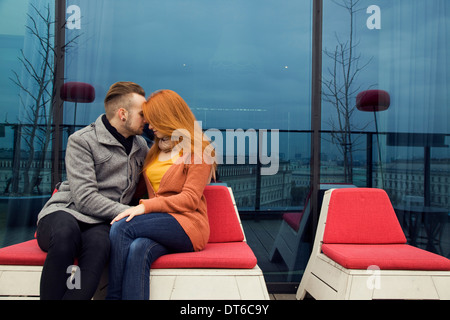 Romantic young couple sitting outdoors on rooftop terrace Stock Photo