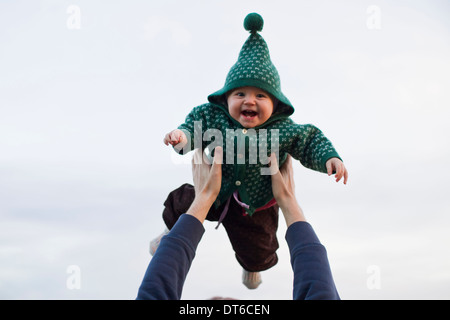 Father lifting baby daughter against sky Stock Photo