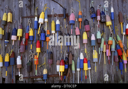 Fishing marker marine buoys or floats hanging on a fishing shed wall on the waterfront. Stock Photo