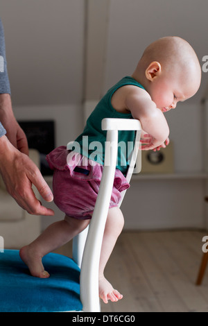 Baby girl standing on chair Stock Photo