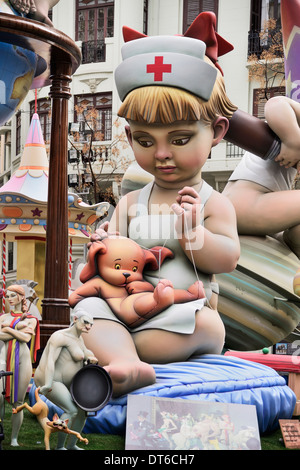 Spain, Valencia, Papier Mache figure of young girl in nurses outfit with teddy bear in the street during Las Fallas festival. Stock Photo