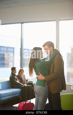 Young couple hugging in airport Stock Photo