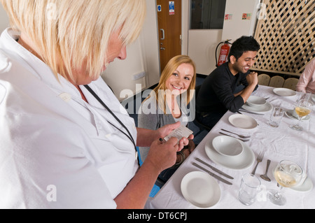 Group of people sat around a dinner table ordering food Stock Photo