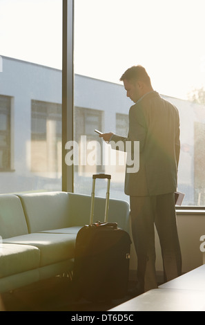 Mature man in airport using cell phone Stock Photo