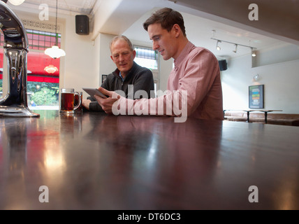 Father and son using digital tablet in bar Stock Photo
