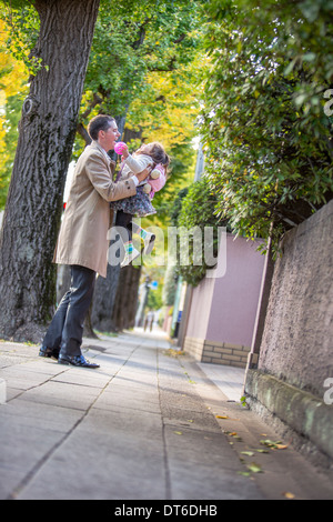 Father lifting daughter on pavement Stock Photo