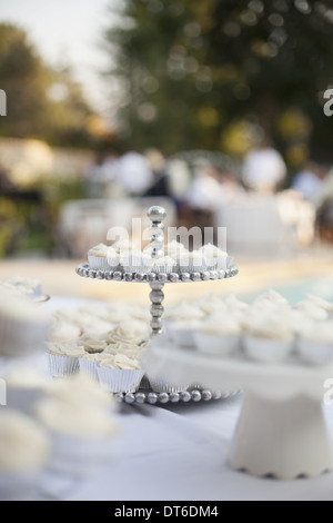 A table laid for a banquet or a wedding breakfast. White table cloth, cake stand, and table setting. Stock Photo
