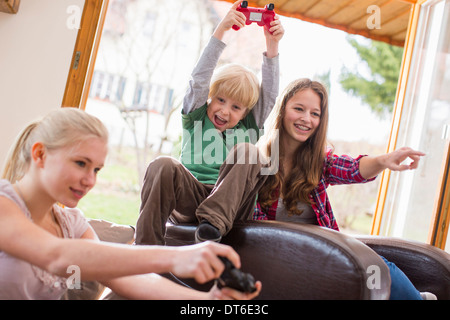 Teenage girls and boy playing games console Stock Photo