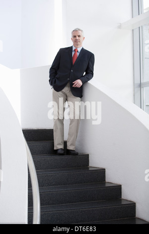 Portrait of mature businessman on office stairs Stock Photo