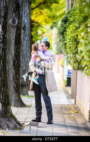 Father carrying daughter on pavement Stock Photo