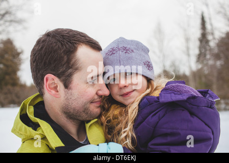 Father holding daughter in snow Stock Photo