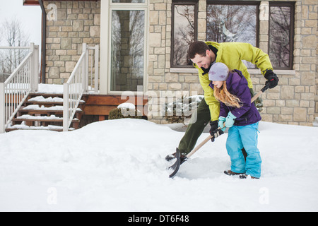 Father helping daughter to shovel snow Stock Photo