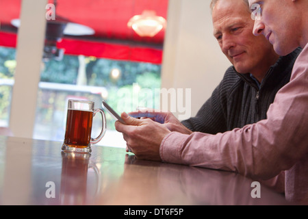 Father and son using digital tablet in bar Stock Photo