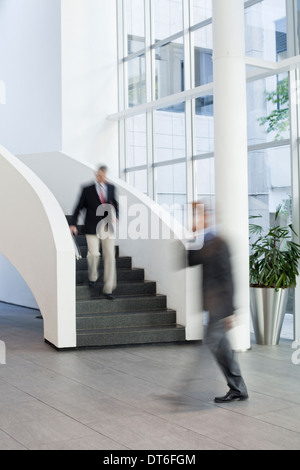 Businessmen on the move in office atrium Stock Photo