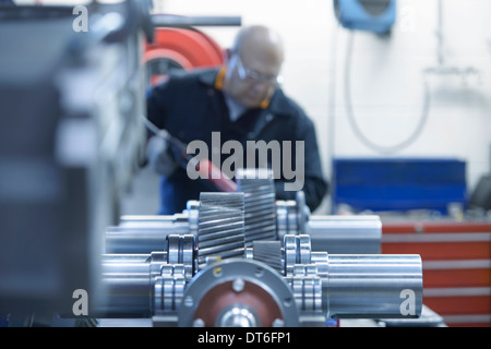 Engineer applying sealant to industrial gearbox in factory