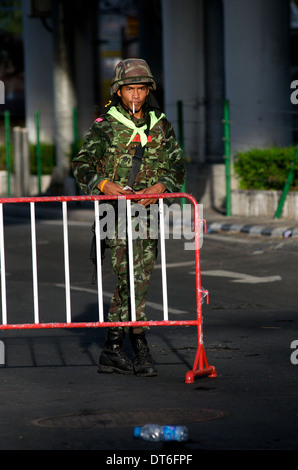 Thai military standing guard, cigarette in mouth, Red shirt protest, Ratchaprasong intersection, Rama 1 Road, Bangkok, Thailand. Stock Photo