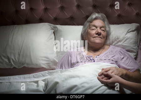 Young woman holding sleeping senior woman's hand Stock Photo