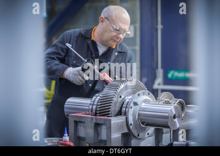Engineer applying sealant to industrial gearbox in factory