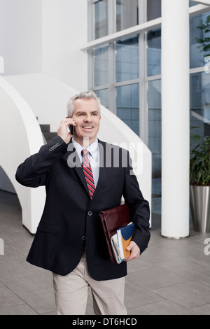 Businessman chatting on cellphone in office atrium Stock Photo