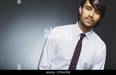 Image of young male model in formal wear looking at camera. Mixed race businessman posing against grey background. Stock Photo