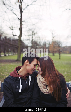 teenage couple sitting on a bench and enjoying a day in the park beautiful dt6j4m
