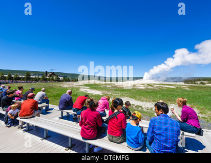 Tourists at Old Faithful Geyser with Old Faithful Inn behind, Upper Geyser Basin, Yellowstone National Park, Wyoming, USA Stock Photo