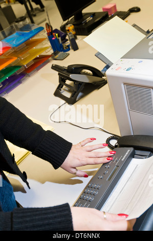 Woman in an office using a fax machine Stock Photo