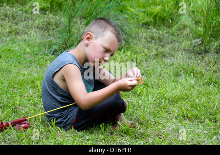 young boy male child baiting a fish hook fishing rod Stock Photo