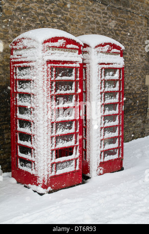 A pair of BT Red Telephone boxes partly covered in snow. Stock Photo