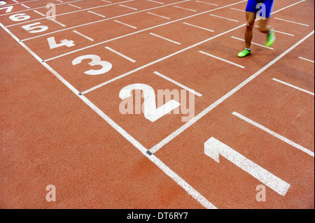 Blurred athlete by a slow camera shutter speed crossing the finish line after sprint track Stock Photo