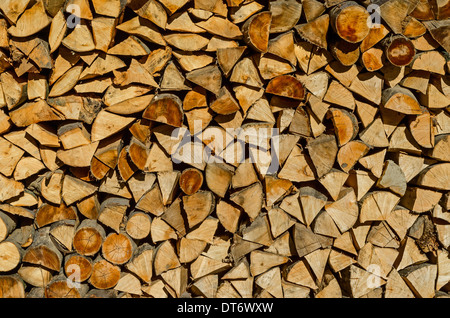 Background of dry chopped firewood logs stacked up on top of each other in a pile Stock Photo