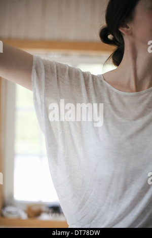 A woman wearing a light tee shirt, with her hair neatly tied back in a clip.  Stretching out her arms. Stock Photo