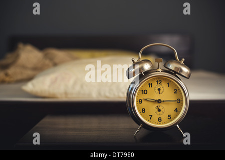 Vintage alarm clock in bedroom on a night table by the bed. Stock Photo