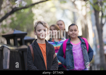 A group of children on the sidewalk, carrying bags. Stock Photo