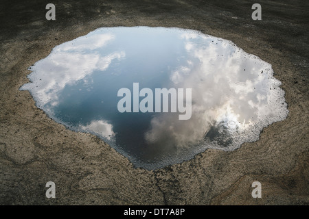 Rain drops falling onto a large puddle A reflection of sky and clouds Elko County Nevada USA Stock Photo
