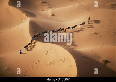 setting sun over desert shadow as a caravan camel merchants winds their way toward the next stop on their journey Sahara Desert Stock Photo