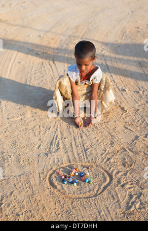 Young Indian girl playing marbles in a rural Indian village. Andhra Pradesh, India.  Selective focus Stock Photo