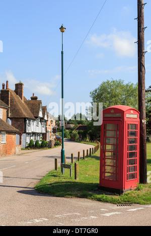 Traditional old red telephone box and telegraph pole on a village green in Chartham, Kent, England, UK, Britain Stock Photo