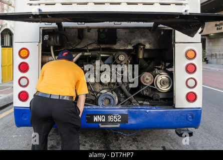 Man looking at a bus engine Stock Photo
