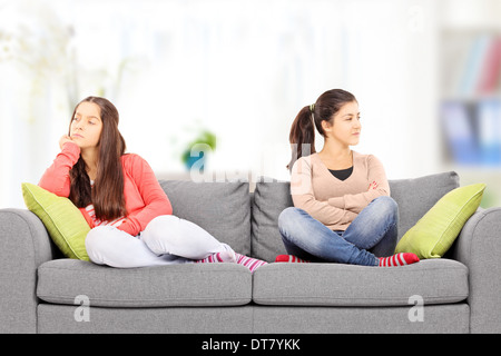 Two teenage girls sitting on sofa, at home, angry with each other Stock Photo