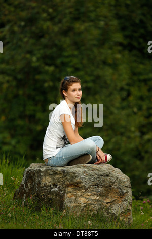 Young girl siting on a stone. Stock Photo