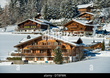 Swiss chalets in the winterly landscape of the Saanenland, Schoenried, canton of Bern, Switzerland Stock Photo