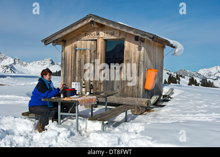 Open-air cheese fondue at the fondue chalet on the Schoenried Fondue Trail in the winterly Saanenland, Switzerland Stock Photo