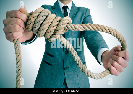 man wearing a suit holding a rope with a hangmans noose Stock Photo
